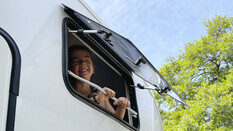 Ein Kind lacht aus dem Wohnwagen-Fenster.