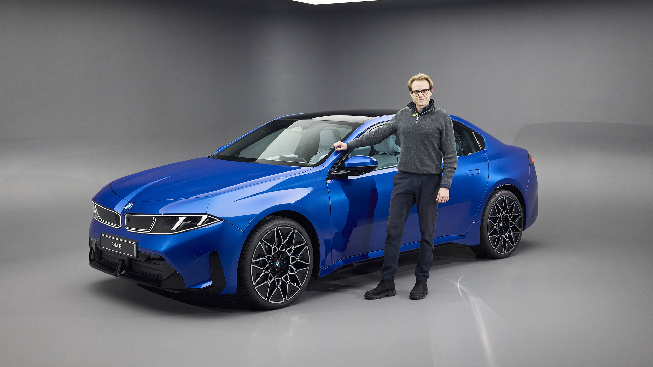 Eine Person steht vor einem blauen BMW i3, der in einem Studio steht.