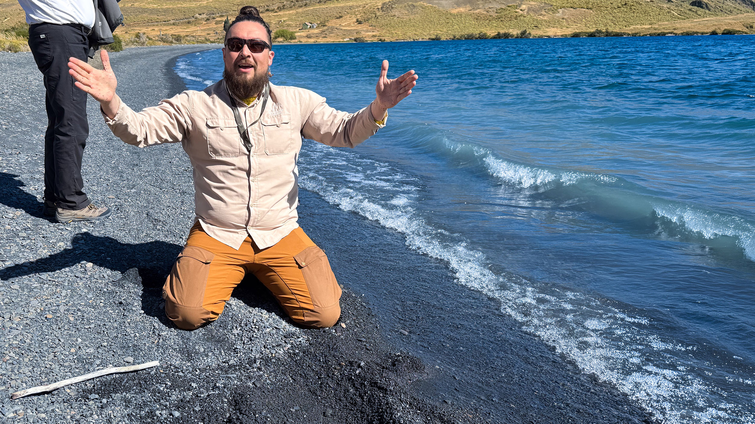 Guide Collins kniet im scharzen Lavasand am Ufer der Laguna Azul und formt anschaulich die Entstehung der Anden