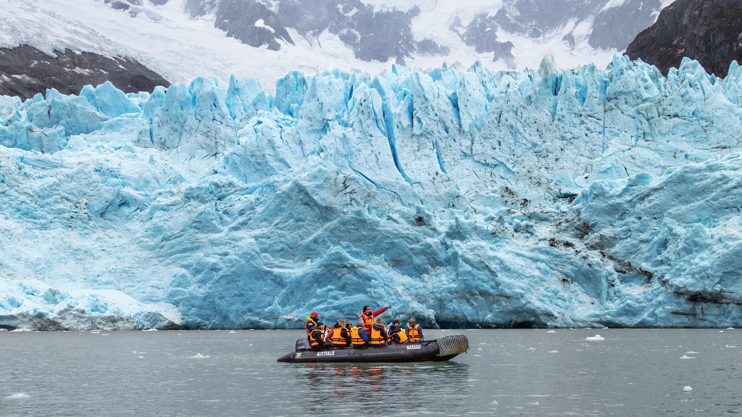 Zodiac mit Passagieren mit orangen Schwimmwesten vor dem türkis-blau-weißen Porter-Gletscher