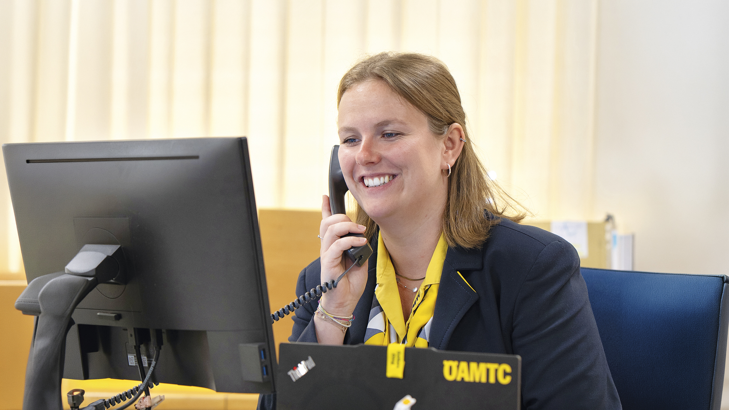 Reisebürokauffrau Katharina Wiesbauer am Telefon, wie sie auf den Computerbildschirm blickt.