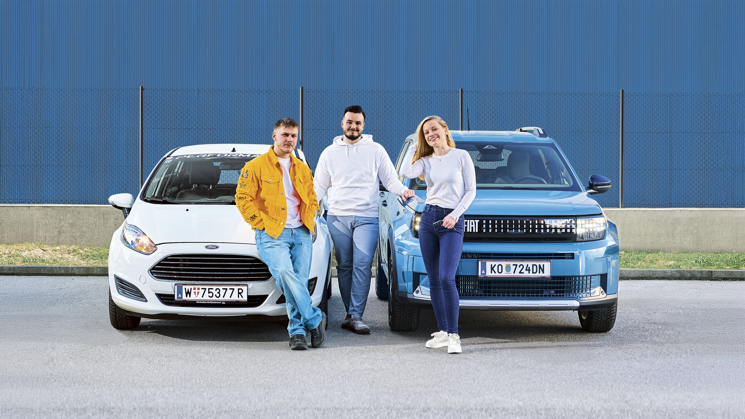 Paul, Marko und Stephanie lehnen an zwei Autos, ein weißer Ford Fiesta und ein grün-grauer Fiat Grande Panda.
