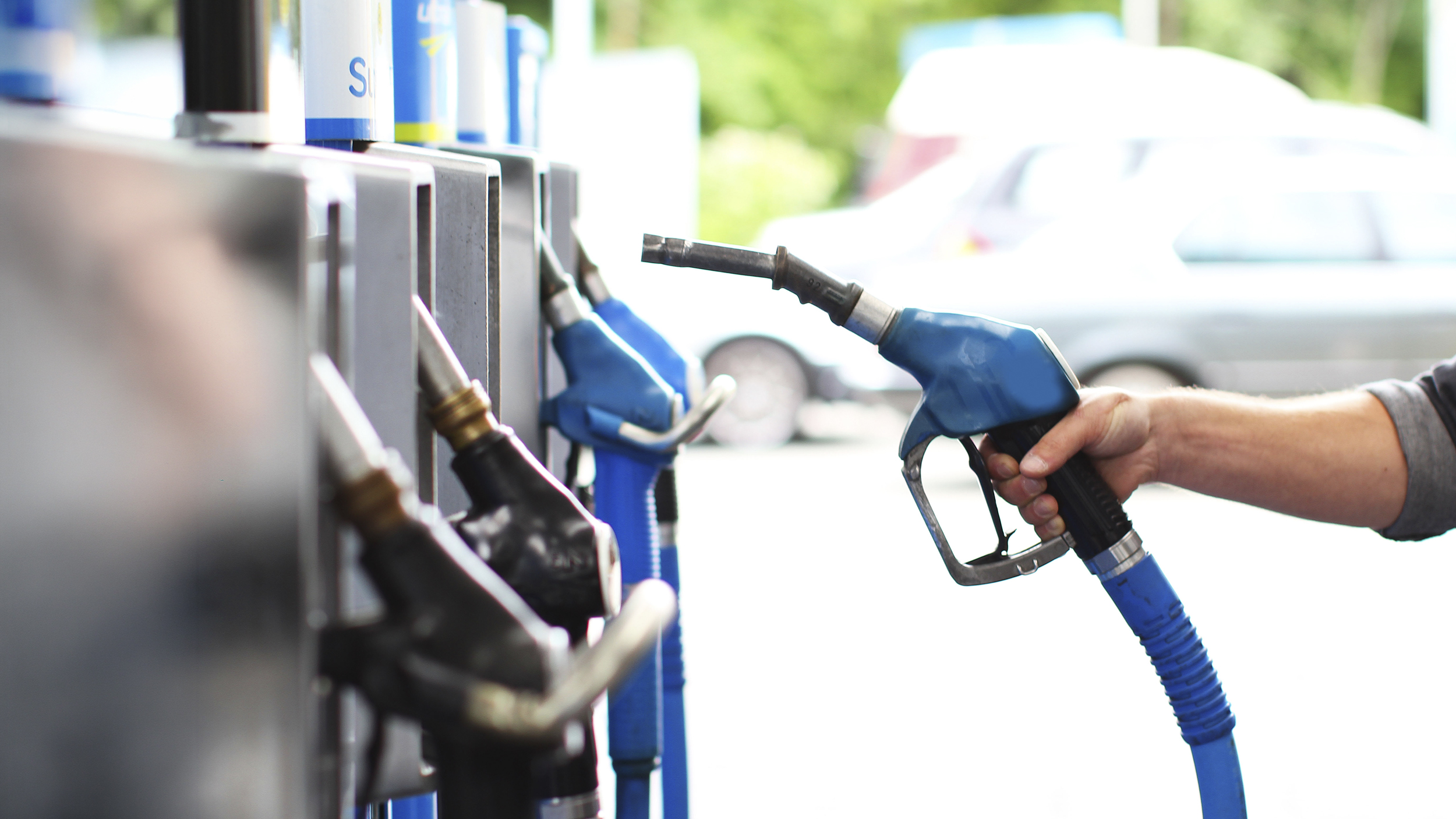 Eine Hand nimmt den Tankstutzen in die Hand an einer Tankstelle.