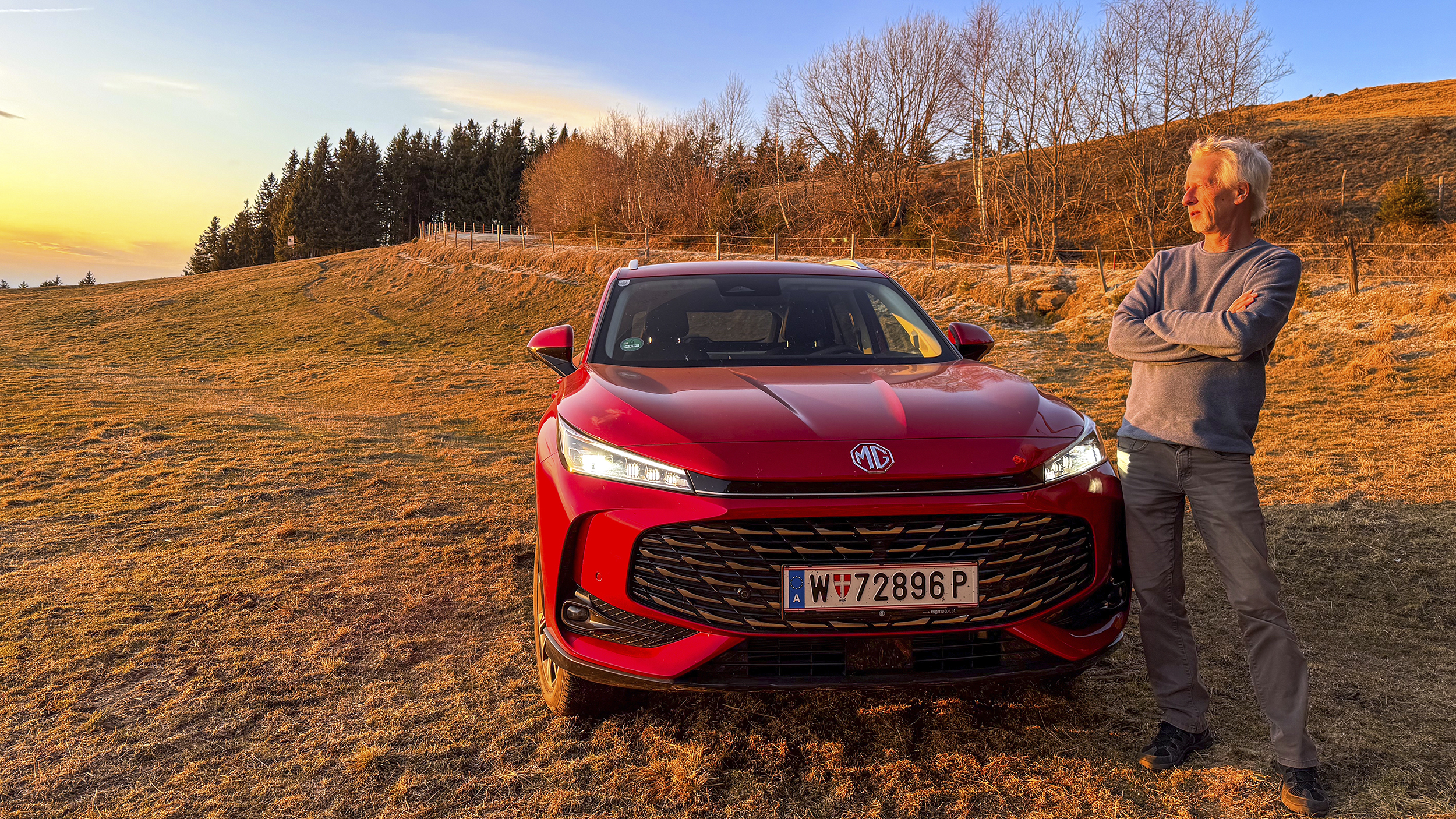 Bild zeigt einen auto-touring Redakteur bei Sonnenuntergang vor dem Testauto stehend.