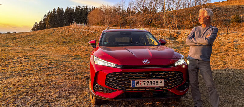 Bild zeigt einen auto-touring Redakteur bei Sonnenuntergang vor dem Testauto stehend.