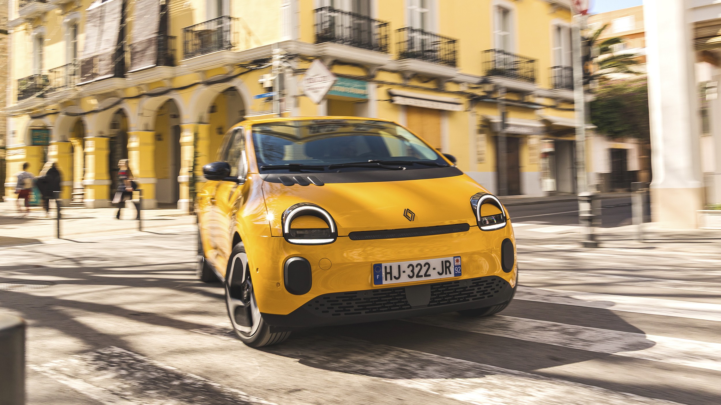 Ein gelber Renault Twingo fährt um eine Kurve in der Stadt.