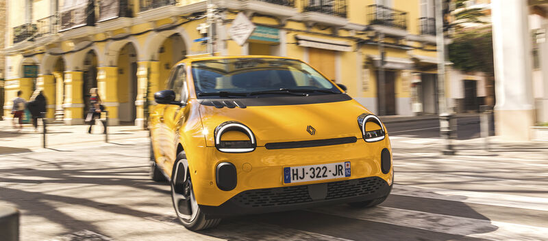 Ein gelber Renault Twingo fährt um eine Kurve in der Stadt.