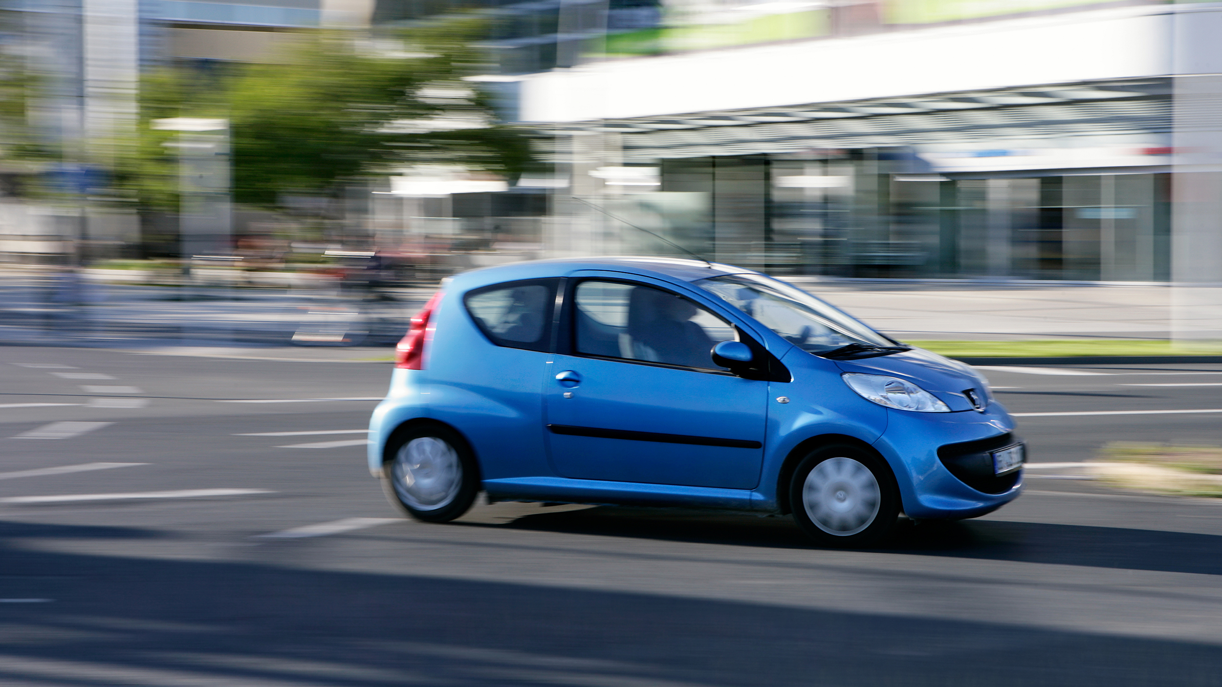 Ein blauer Kleinwagen fährt durch die Stadt
