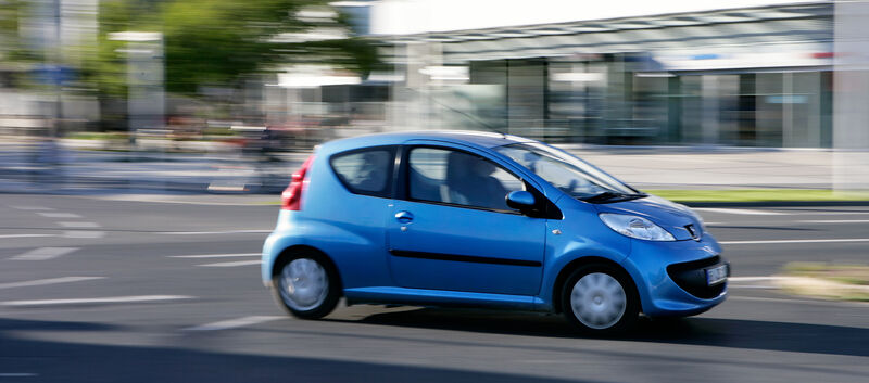 Ein blauer Kleinwagen fährt durch die Stadt