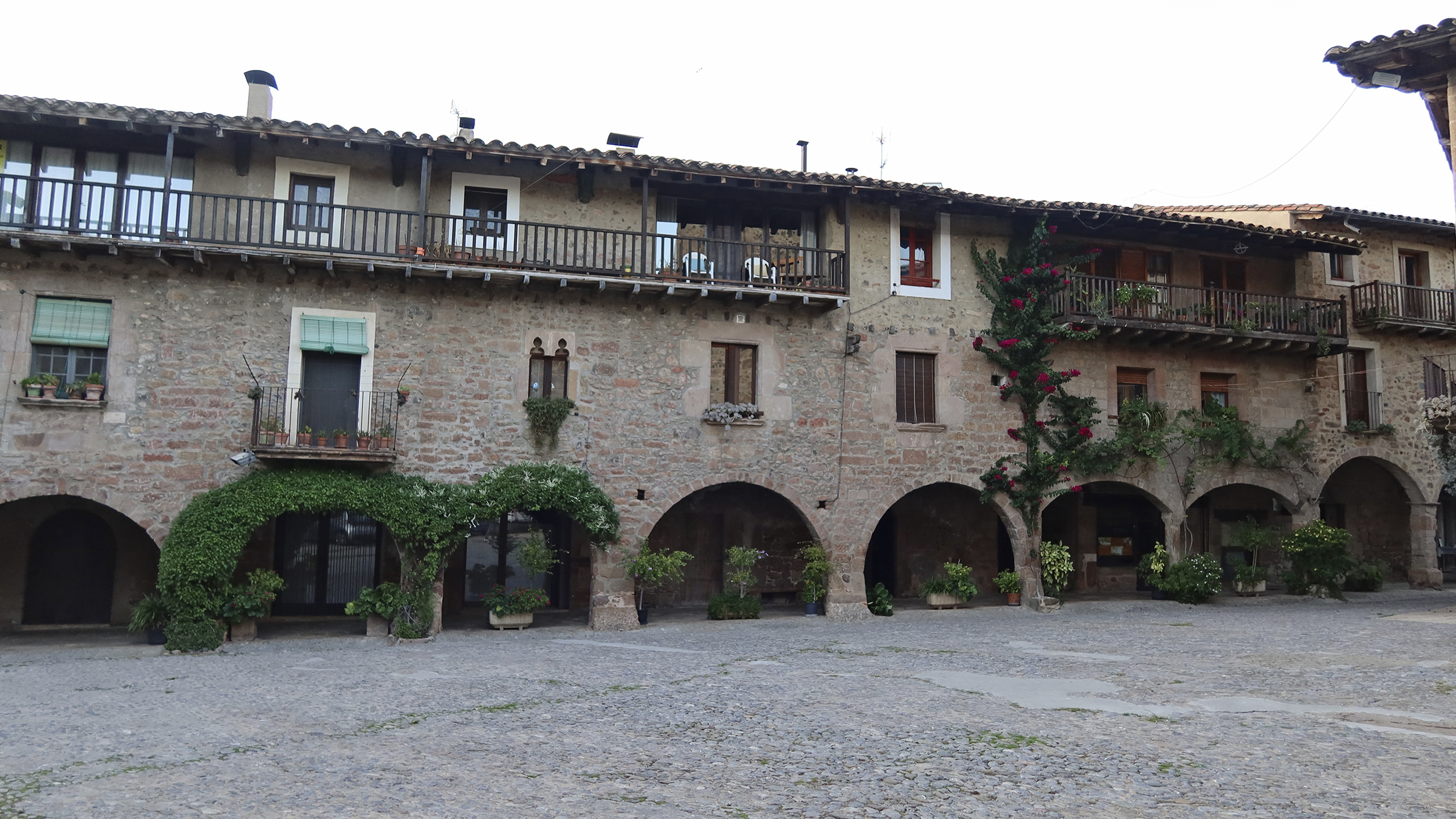 Hotel Cal Sastre in Santa Pau von außen. Mittelalterliches Gebäude aus Stein mit Arkadenbögen.