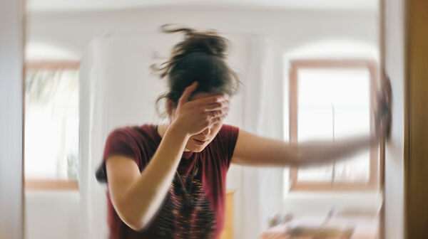 Verschwommenes Foto einer Frau, die unter Schwindel oder Benommenheit leidet, ausgelöst durch eine Erkrankung des Gehirns oder des Innenohrs.