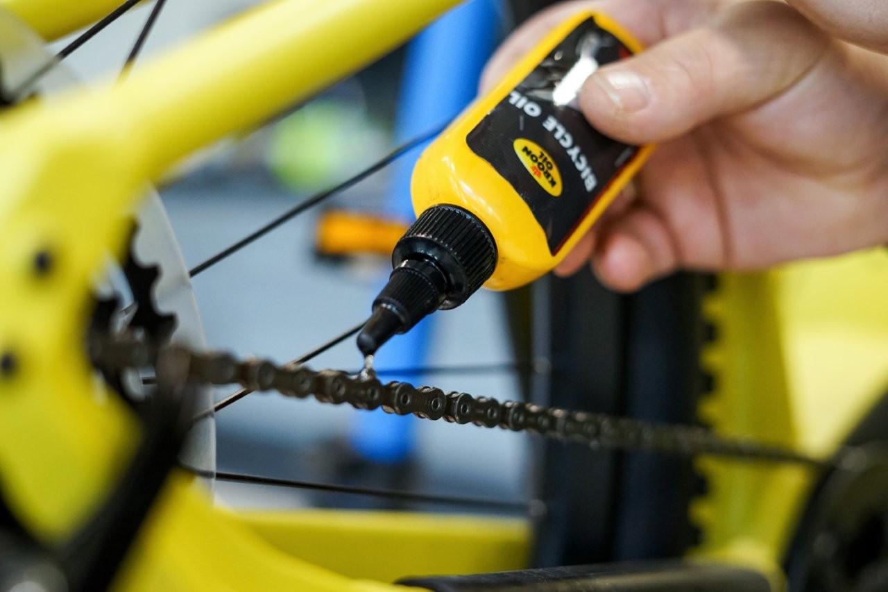 Auf dem Bild sieht man eine Hand die eine Fahrradkette ölt
