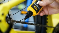 Auf dem Bild sieht man eine Hand die eine Fahrradkette ölt
