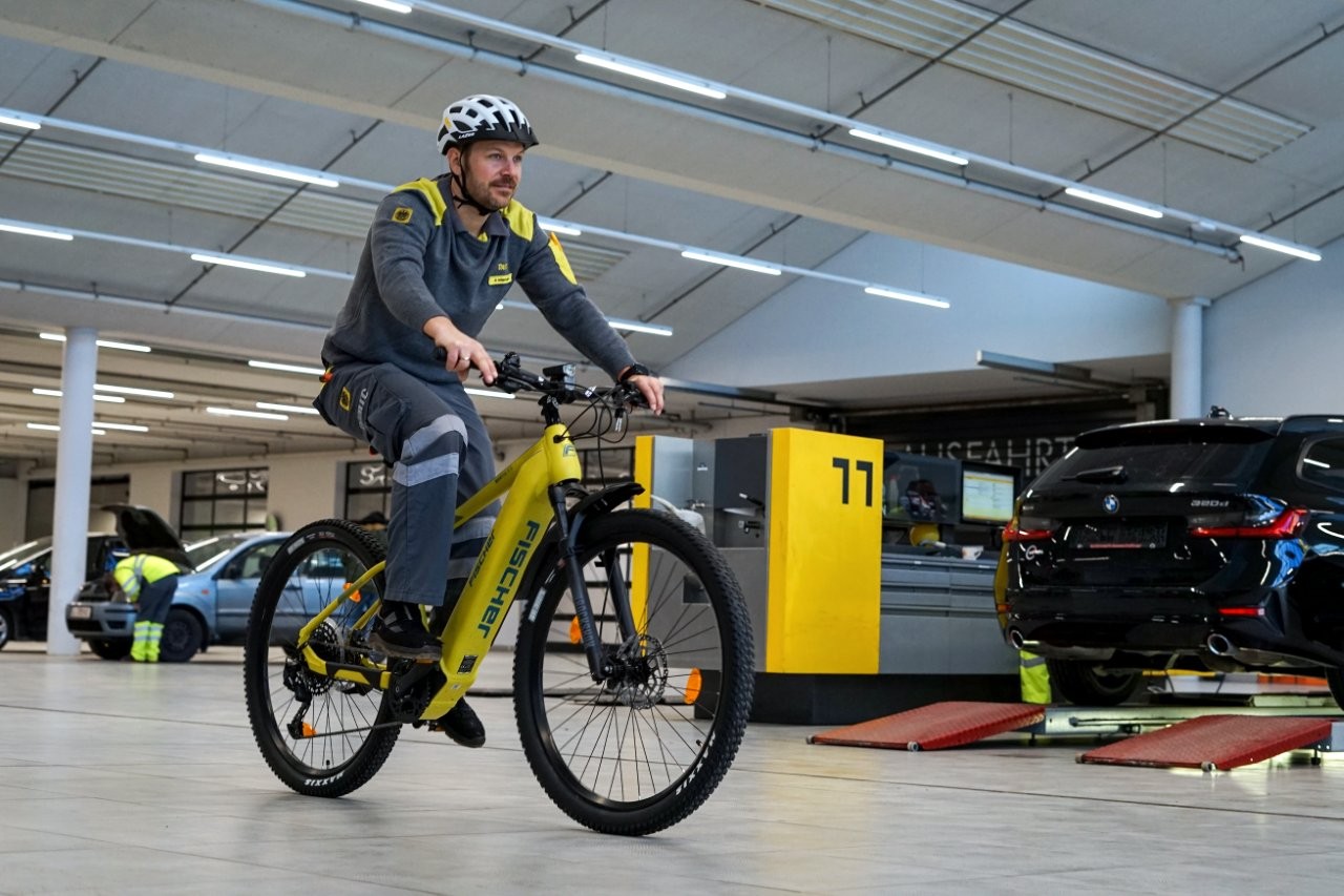 Auf dem Bild sieht man einen ÖAMTC Mitarbeiter mit Helm auf einem Fahrrad