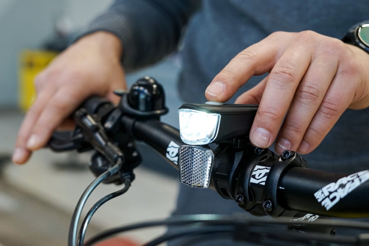 Auf dem Bild sieht man eine Hand die eine Fahrradlampe einschaltet.