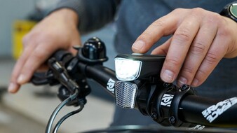 Auf dem Bild sieht man eine Hand die eine Fahrradlampe einschaltet.
