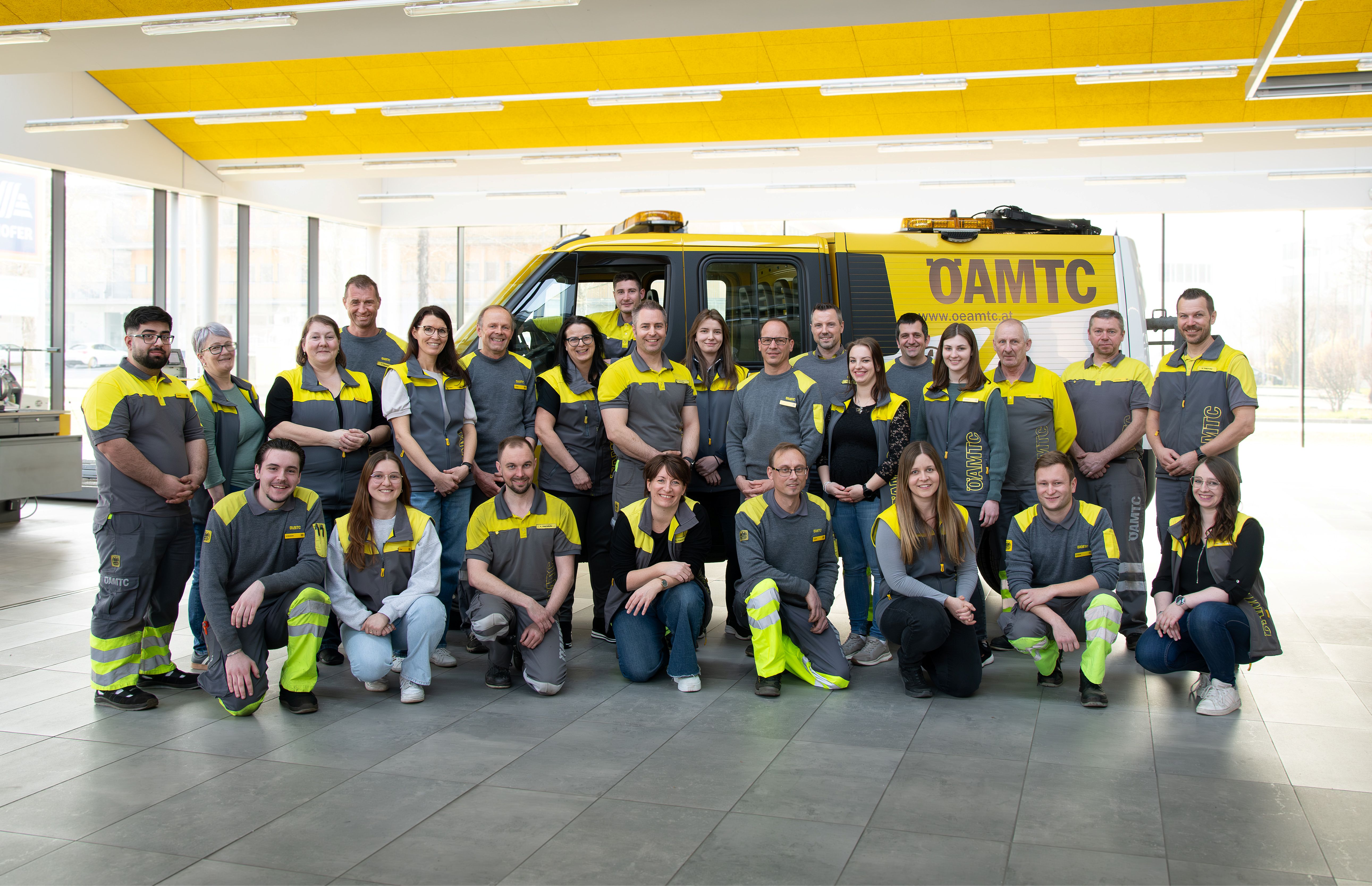 Die Kolleginnen und Kollegen vom Stützpunkt Urfahr stehen vor einem Pannenfahrzeug für ein Teamfoto.