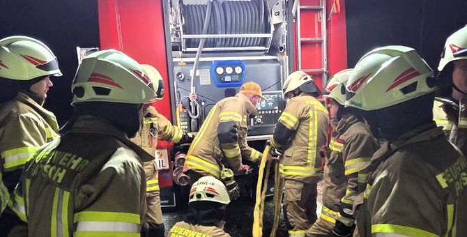Auf dem Bild sieht man viele Feuerwehrmänner und Frauen im Einsatz vor einem Fahrzeug der Feuerwehr