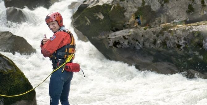 Auf dem Bild sieht man einen Mitarbeiter der Wasserrettung vor einem reißenden Fluß.