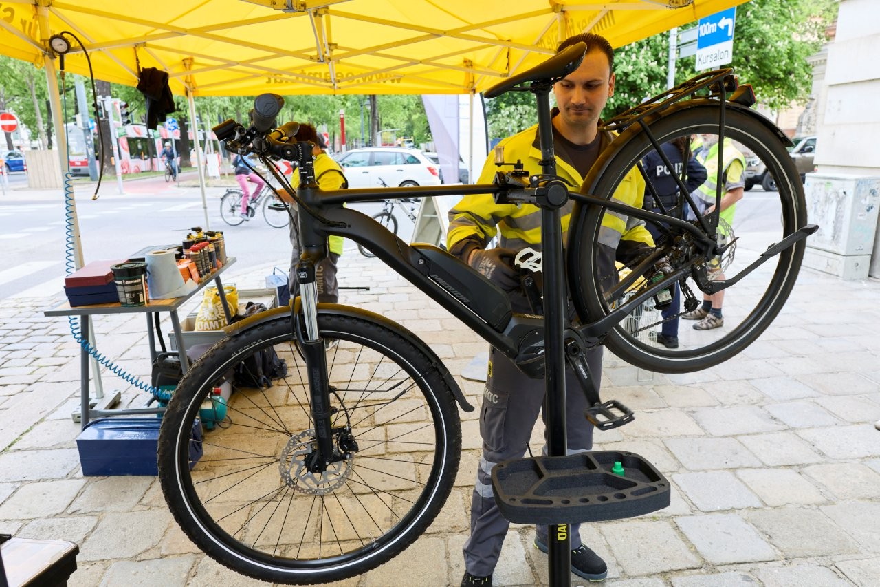 Auf dem Bild sieht man einen Mitarbeiter des ÖAMTC der gerade ein Fahrrad repariert.