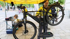 Auf dem Bild sieht man einen Mitarbeiter des ÖAMTC der gerade ein Fahrrad repariert.