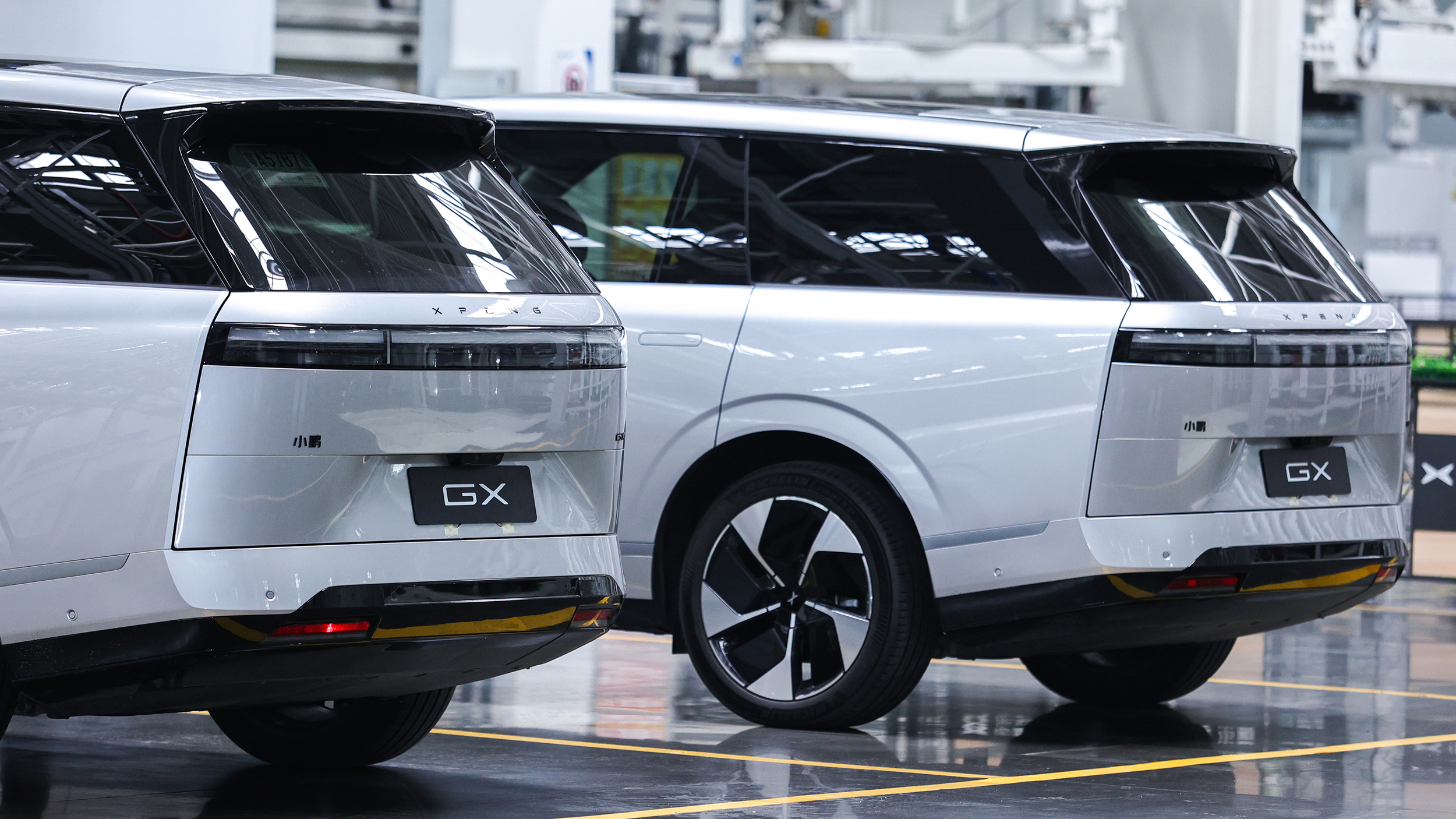 Zwei silberne SUV von hinten in einer Fabrikshalle