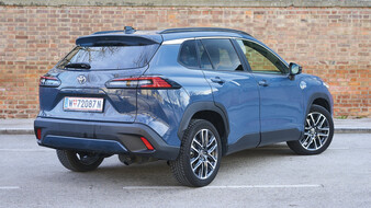 Ein graublaues Toyota-SUV steht vor einer Ziegelwand, von schräg hinten.