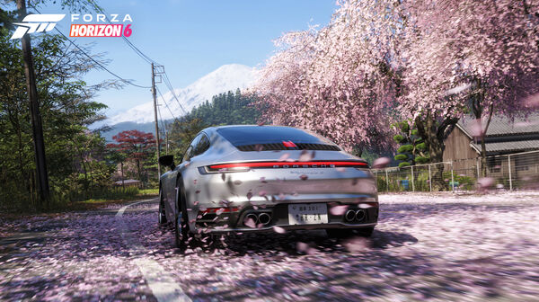 Screenshot aus Forza Horizon 6. Ein silberner Porsche inmitten von Kirschbäumen mit rosa Blüten.
