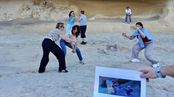 einige Personen stellen am Strand eine Tanzszene aus dem Film nach.