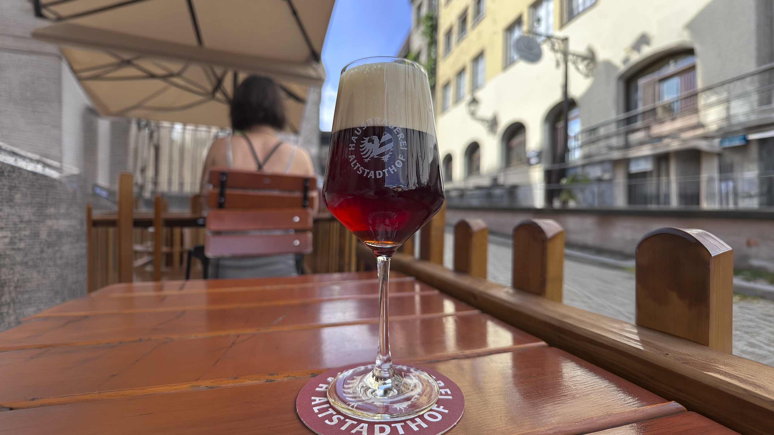 Eine Biertulpe mit rötlich-braunem Bier auf einem Tisch im Gastgarten.