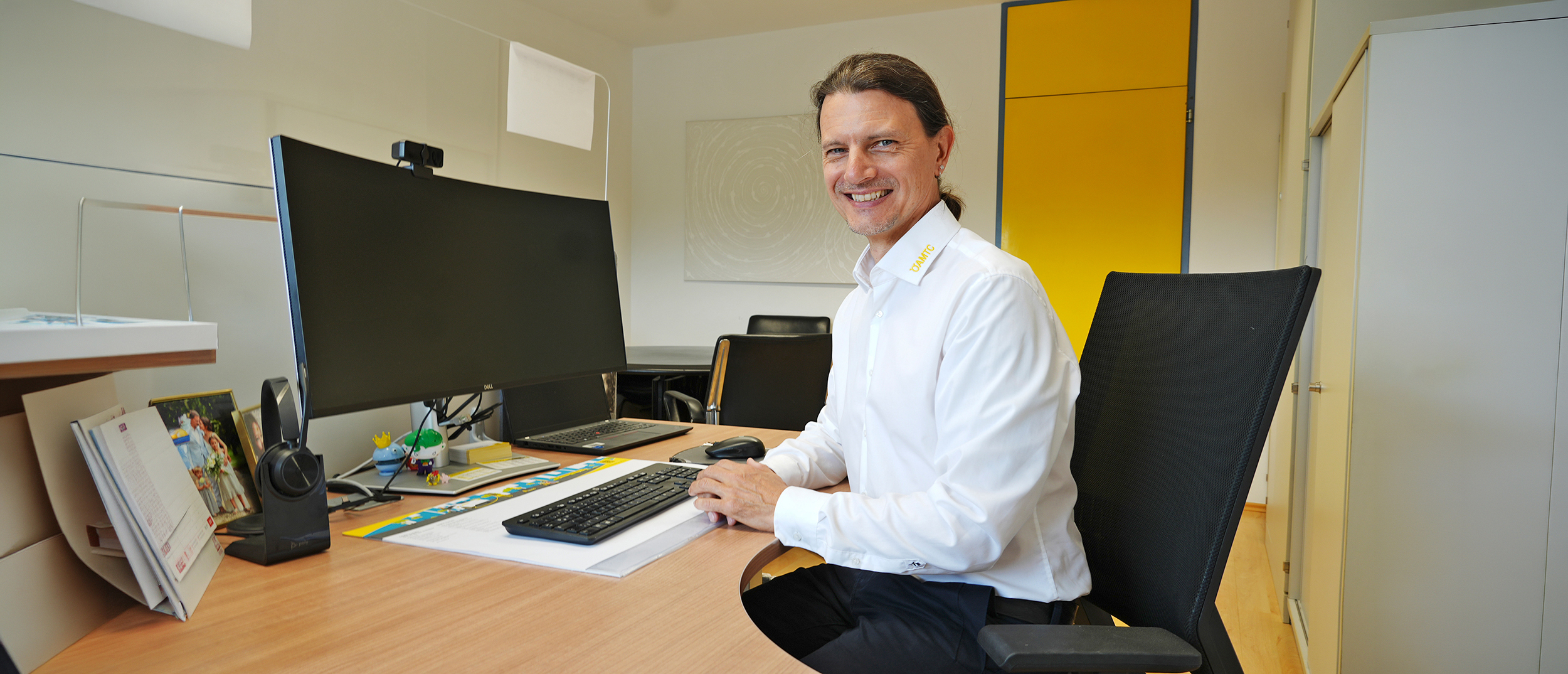 Ein Mann mit weißem Hemd sitzt vor seinem Computer im Büro.