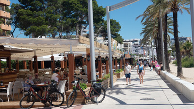 Promenade mit Palmen und Restaurant.
