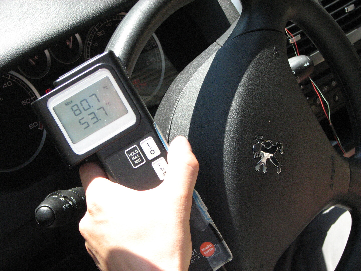 Man sieht ein Temperaturmessgerät, das über einem Auto-Lenkrad positioniert ist und 80 Grad Oberflächentemperatur anzeigt.