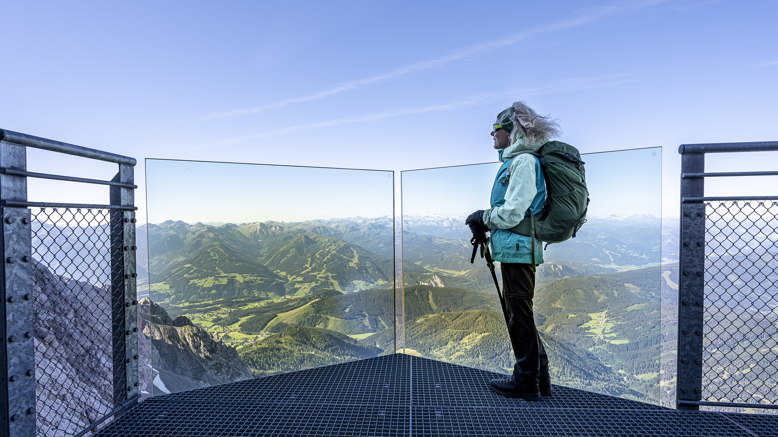 Eine Frau steht auf einer Aussichtsplattform, Blick auf die Berge.