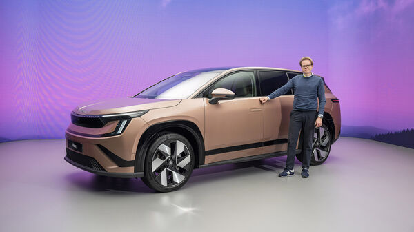Eine Person steht vor einem kupferfarbenen Skoda Peaq.
