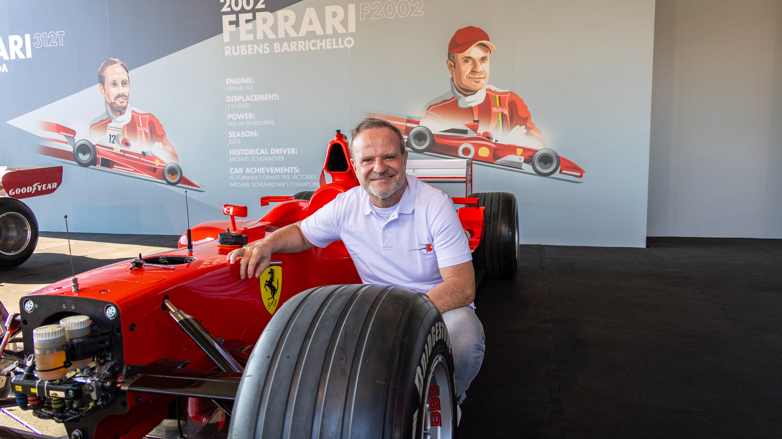 Rubens Barrichello kniet vor einem Formel-1-Ferrari von 2002.