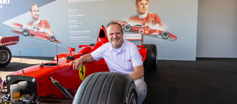 Rubens Barrichello kniet vor einem Formel-1-Ferrari von 2002.