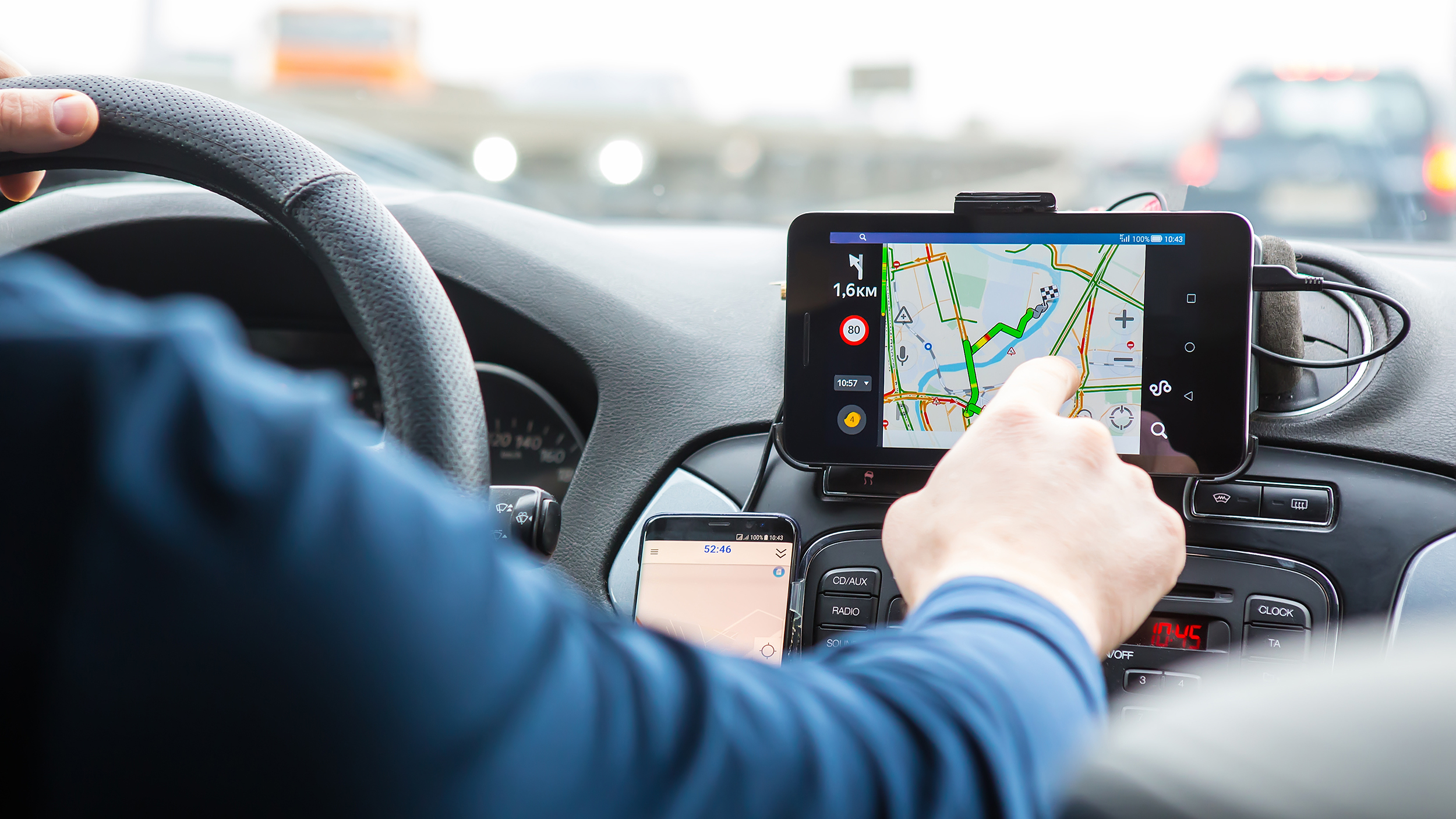 Der Fahrer bedient im Auto ein Navigationsgerät.