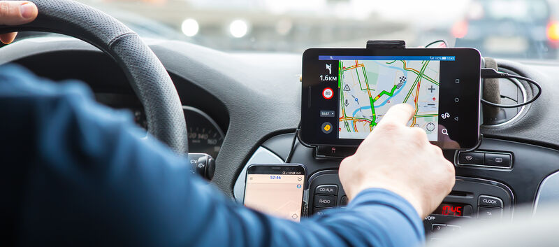 Der Fahrer bedient im Auto ein Navigationsgerät.