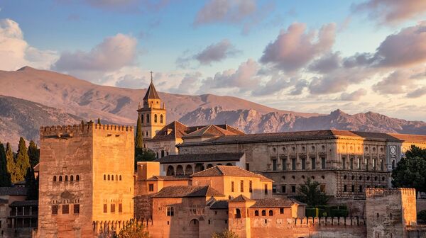 Das Foto zeigt die Alhambra in der Abendsonne vor den Gipfeln der Sierra Nevada.