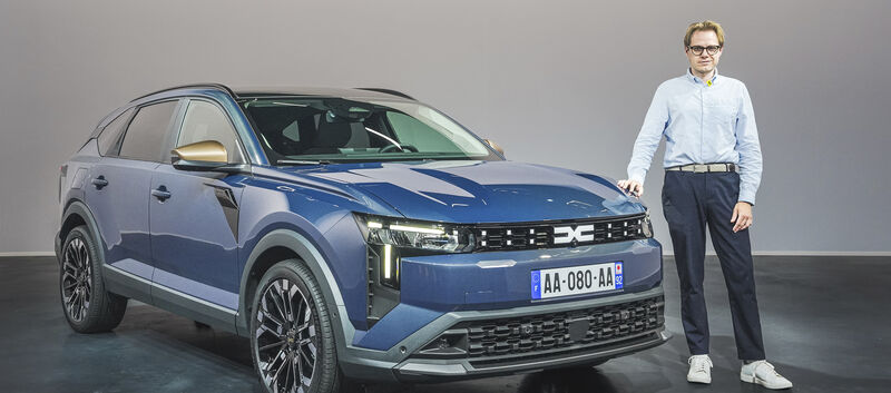 Einee Person im Hemd steht neben einem blauen Dacia Striker.
