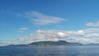 Auf dem Foto ist das Meer in Norwegen zu sehen. In der Bildmitte sieht man eine Insel.
