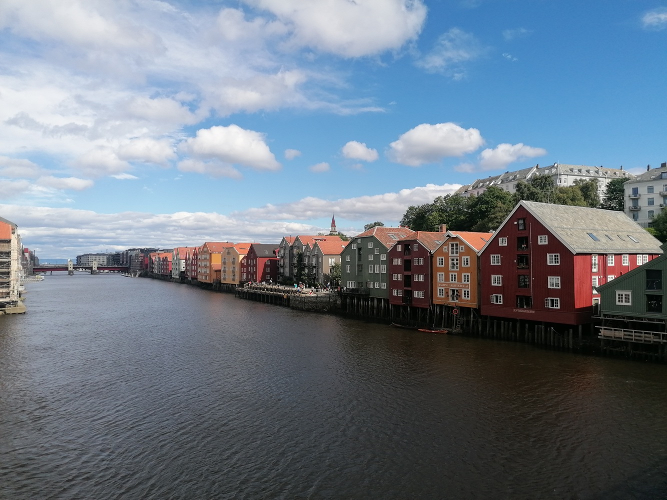 Auf dem Foto sieht man eine Häuserfront mit bunten, norwegischen Häusern, die direkt am Wasser liegen.