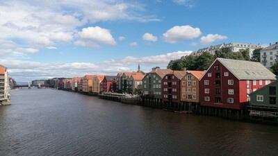 Auf dem Foto sieht man eine Häuserfront mit bunten, norwegischen Häusern, die direkt am Wasser liegen.