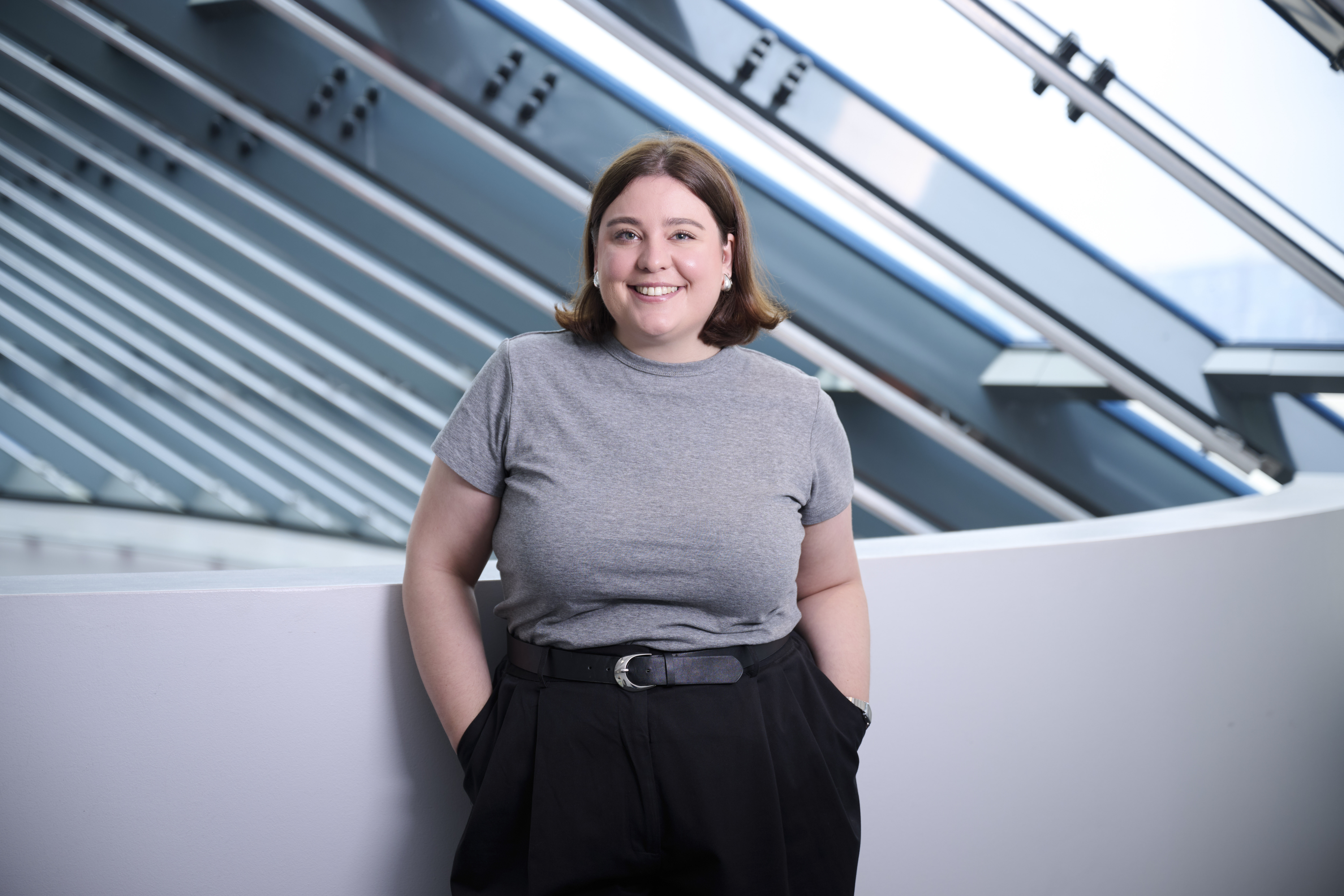Das Bild zeigt eine Frau mit braunen Haare, die eine graues T-shirt trägt.