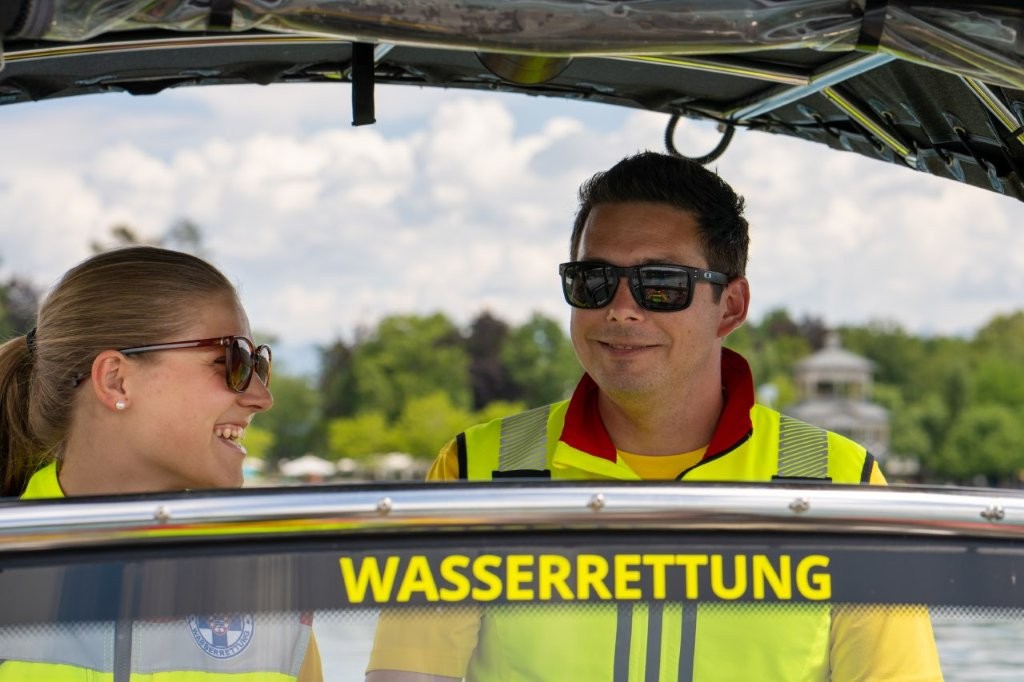 Auf dem Bild sieht man einen Mitarbeiter und eine Mitarbeiterin der Wasserrettung, die gemeinsam auf einem Boot fahren.
