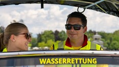 Auf dem Bild sieht man einen Mitarbeiter und eine Mitarbeiterin der Wasserrettung, die gemeinsam auf einem Boot fahren.