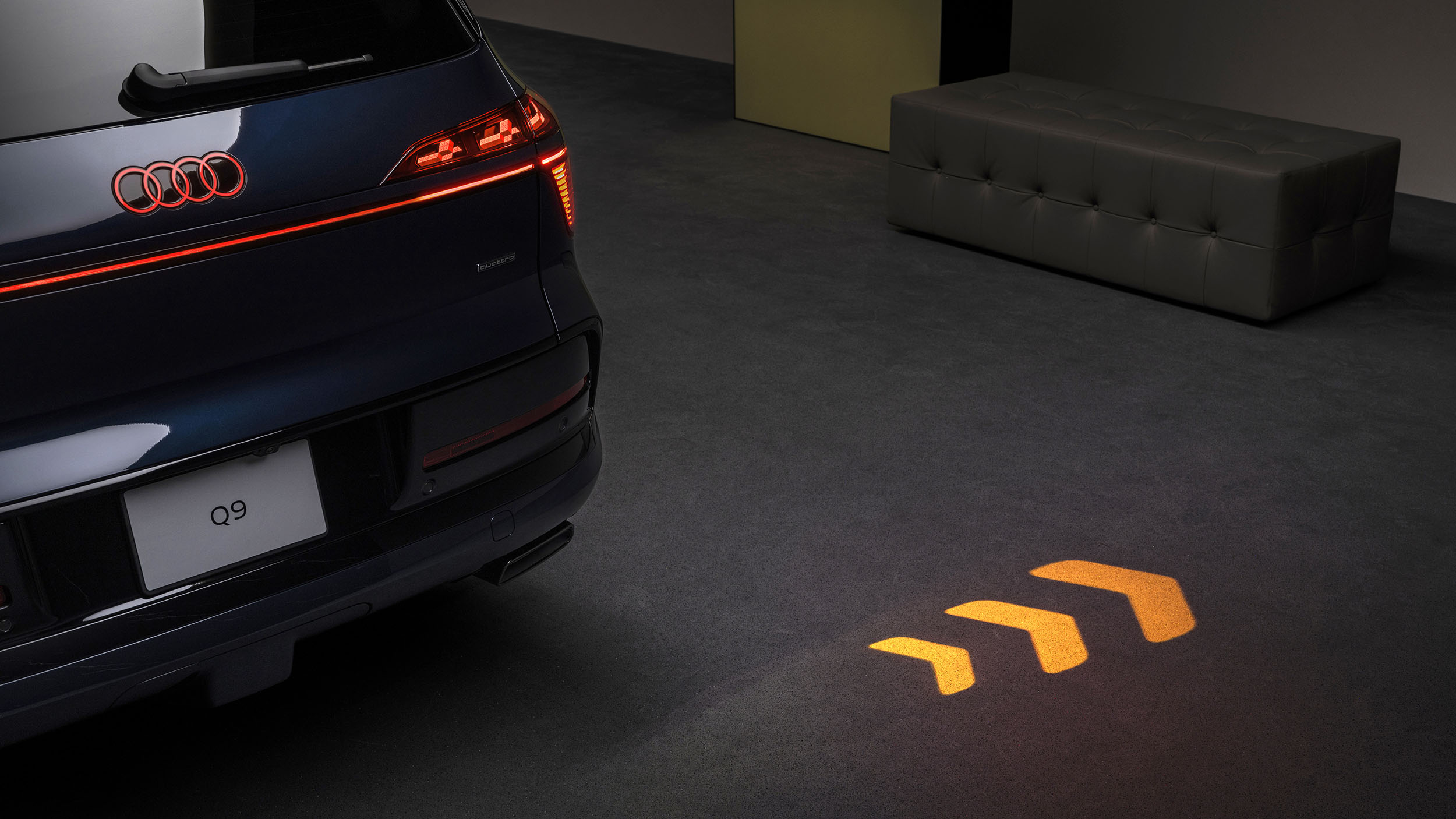Auf Boden projizierte Lichtsignatur eines blauen Audi Q9.