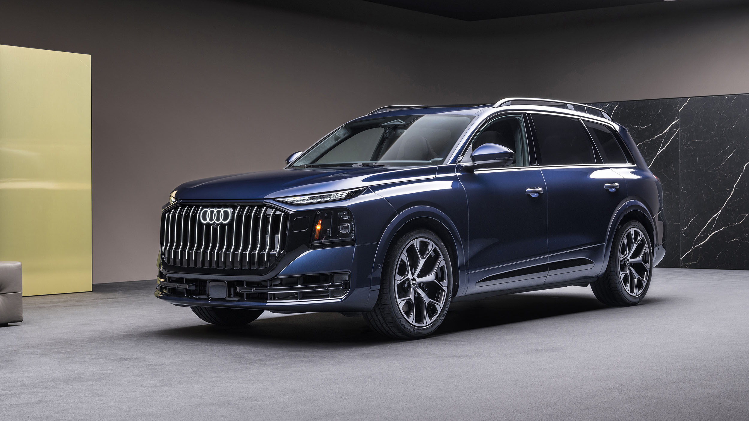 Ein blauer Audi Q9 steht in einem Studio.