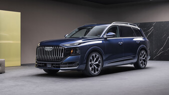 Ein blauer Audi Q9 steht in einem Studio.